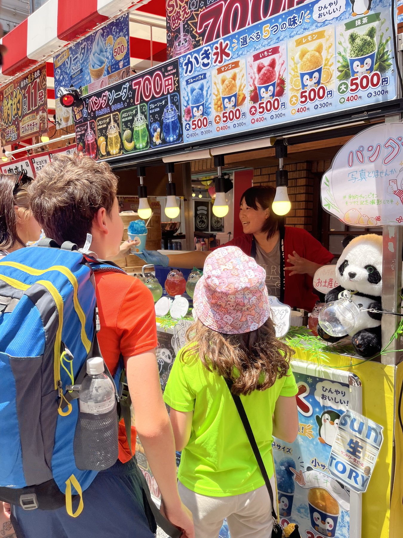 Children choosing a colorful treat at a Kobe market